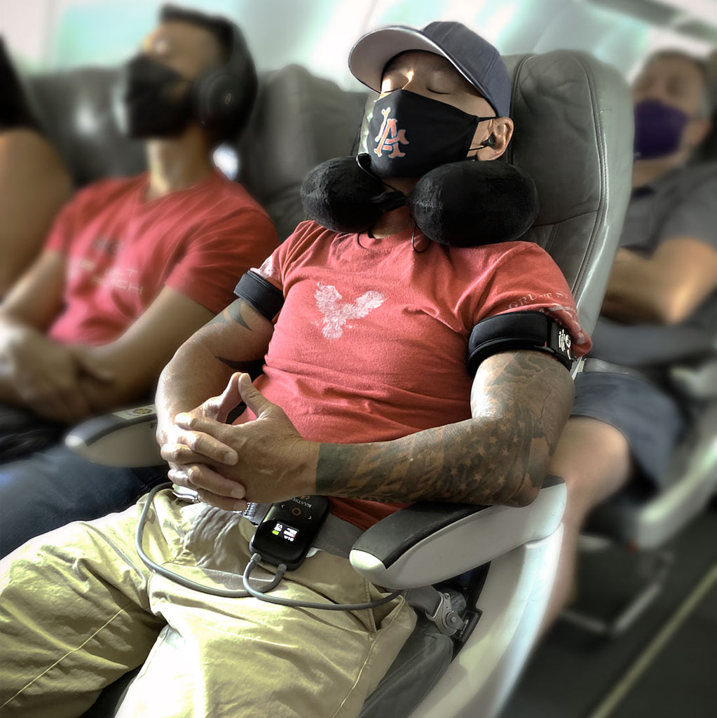 A man asleep on a plane using KAATSU BFR for blood flow restriction training.